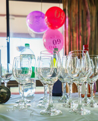 60th birthday balloons hanging from the window, selective focus on wine glasses on the table. Birthday celebration. Vertical format.