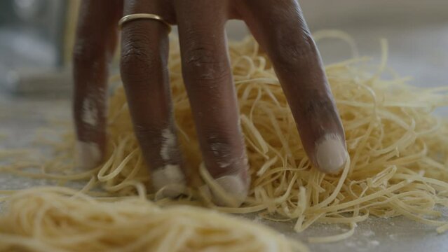 Woman hand sprinkles flour on fresh home made pasta. Cooking, Making pasta process, close up. African American woman making homemade pasta.