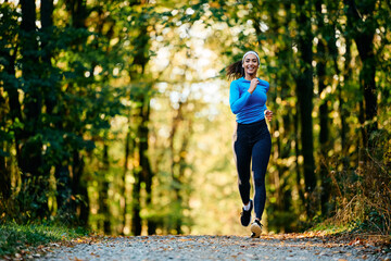 Happy female athlete running in nature.