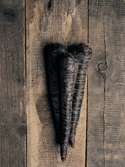 Black root vegetables on a rustic wooden kitchen table view from above