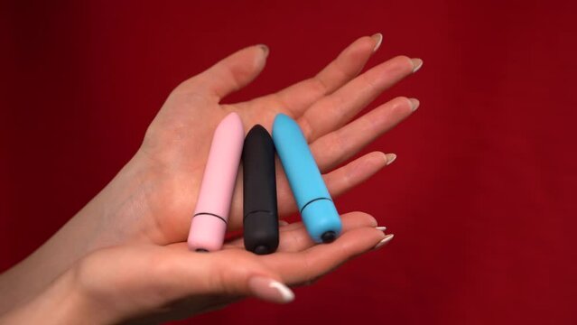 female hands holding Bullet Vibrators isolated on red background.