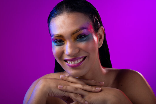 Biracial woman with dark hair, pink lips, eyeshadow make up on purple background