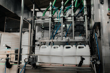 Automatic filling machine pours into plastic PET bottles at modern beverage plant.