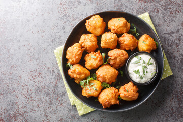 Southern Hush Puppies are light and flakey cornmeal dough that is fried golden brown on the outside and soft on the inside closeup on the plate on the table. Horizontal top view from above