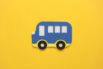 Toy bus made of felt on yellow background.