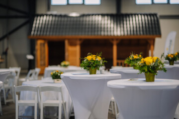 Yellow flowers in a vase grace the white table, their vibrant hues standing out against a softly...