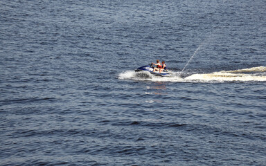 Two men jumps on the  water scooter above the water. Men speeding on powerboat on lake during summer vacation