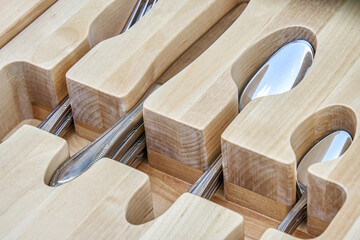 Shiny silverware in craved wooden tray in serving table drawer upper closeup view. Comfortable...