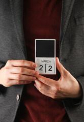 Business man in a jacket holding a calendar with the date March 22
