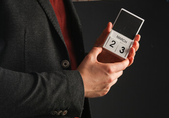 Business man in a jacket holding a calendar with the date March 23