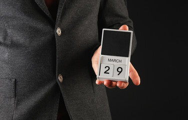 Business man in a jacket holding a calendar with the date March 29