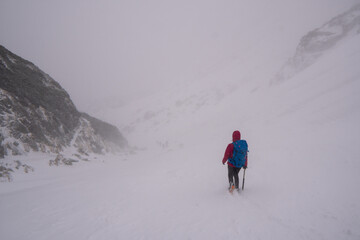 Men with backpack hiking on mountain in snow. Fight for survival in winter mountains. Hiker standing on top of a mountain. Dramatic scenery. Carpathian, Tatras , Europe. Beauty world.