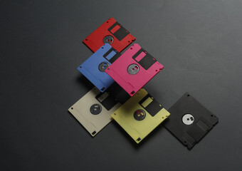 Floating colored retro 80s floppy disks on a dark gray background. Conceptual pop, creative layout