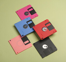 Floating colored retro 80s floppy disks on a green background. Conceptual pop, creative layout