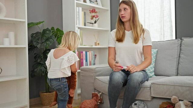 Surprised caucasian mother and daughter relaxing at home, shocked by fever measurement on thermometer