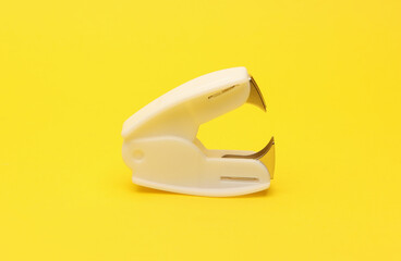 white staple remover on yellow background