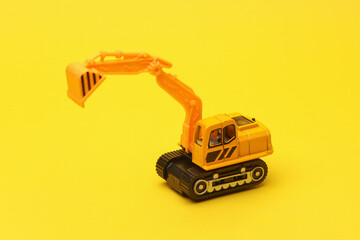 Fototapeta premium Toy excavator on yellow background