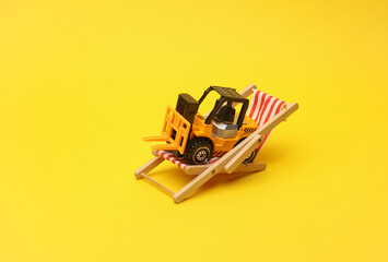 Miniature toy forklift and deck chair on a yellow background. Logistics, vacation concept