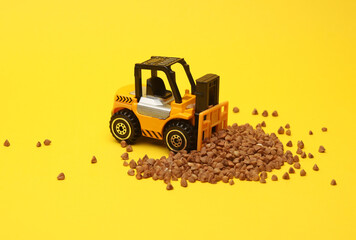 Fototapeta premium Miniature toy forklift and wheat grain on a yellow background.