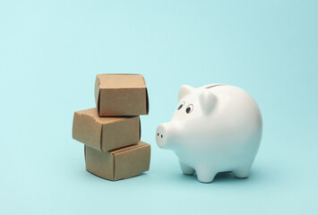 Piggy bank with a stack of boxes on a blue background. Delivery, logistics