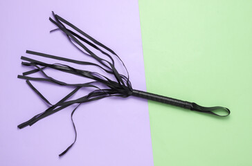 Leather whip on a colored pastel background. Sex games domination