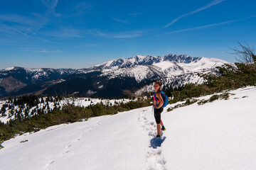 Hiker woman standing with hands up achieving the top, admiring winter mountain landscape. Happy...