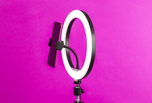 Led ring lamp with smartphone on tripod, purple background. Vlogging, beauty blog