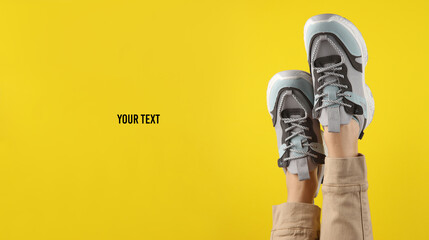 Women's legs in trendy sneakers with massive soles, yellow background. fashion shot. Copy space