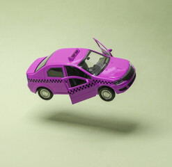 Miniature taxi car levitating on a green background with a shadow