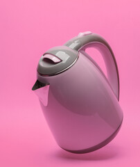 Electric kettle levitates on pink background with shadow