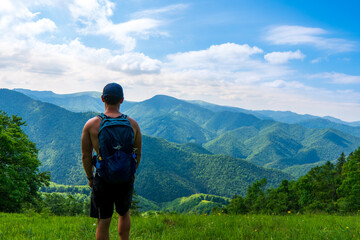 Young man hiking in the beautiful fresh green mountains