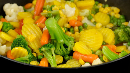 Colorful steaming vegetables frying on a pan. Healthy food, vegetarian cuisine