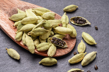 Seeds of cardamom spices in wooden spoon.