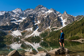 Man tourists in mountains at Morskie Oko lake near Zakopane, Tatra Mountains, Poland. - obrazy, fototapety, plakaty