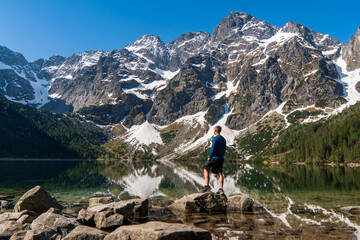 Man tourists in mountains at Morskie Oko lake near Zakopane, Tatra Mountains, Poland. - obrazy, fototapety, plakaty