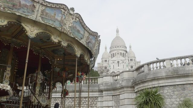 Classic carousel spinning and in the background a large church. Montmatre carousel in Paris.