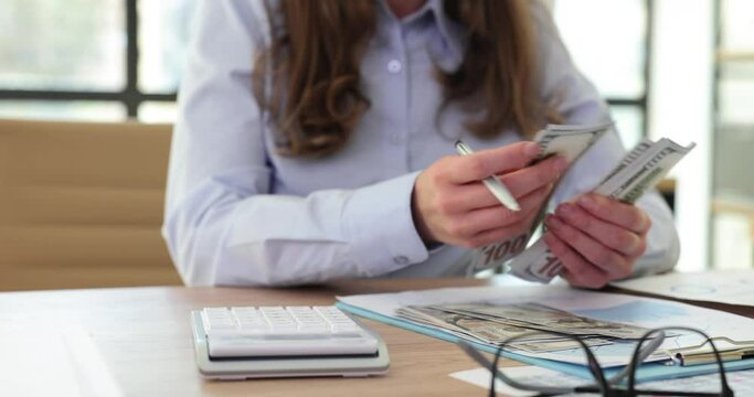 Closeup of woman counting money on calculator and holding of money