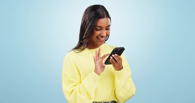 Phone, networking and young woman in studio typing message on social media or mobile app. Technology, research and Indian female model scroll on mobile app with cellphone isolated by blue background.