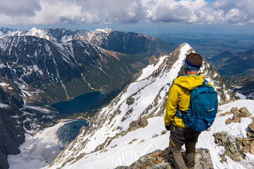 Hiker man standing with hands up achieving the top, admiring winter mountain landscape. Happy tourist woman in winter. High Tatras, 2499 meter above sea level. rysy Poland, Slovakia