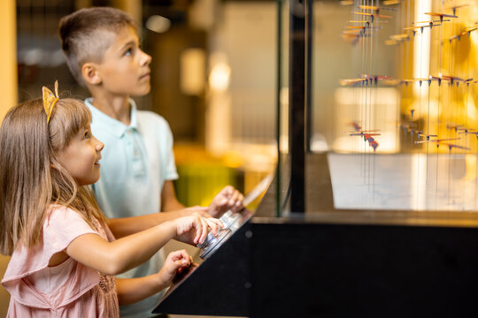 Little boy and girl studying physics and magnetic field on an interactive model in the science museum. Concept of children's entertainment and learning