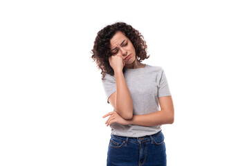 young tired slender 30 year old caucasian woman with curly hair in a gray t-shirt on a white background with copy space