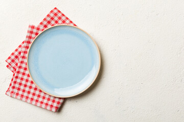 Top view on colored background empty round blue plate on tablecloth for food. Empty dish on napkin with space for your design