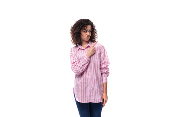 young european curly brunette woman in a pink shirt looks away on the background with copy space