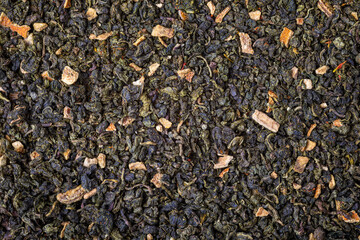 Fototapeta premium Dried natural large tea leaves close up. Chinese tea Tie Guan Yin, with the addition of orange pieces.