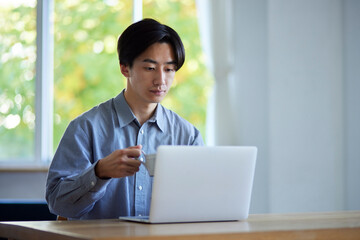 リビングでパソコンを使用する日本人大学生の男性