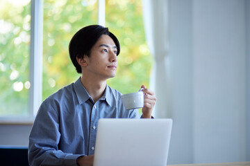 リビングでパソコンを使用する日本人大学生の男性