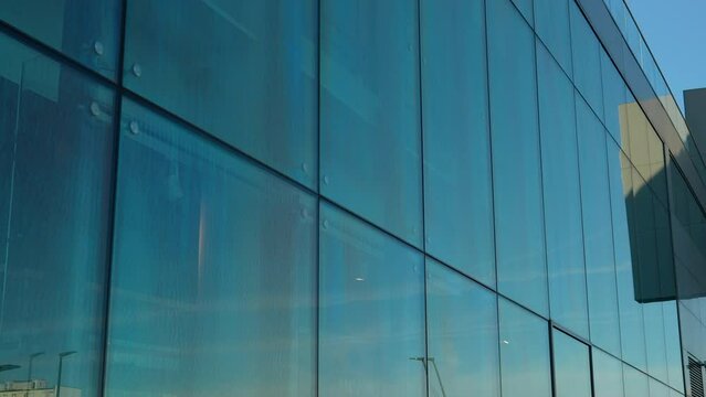 Blue sky reflected in the large glass panels of a modern building's exterior wall.