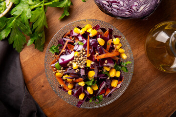  Fresh salad with red cabbage, carrots, hemp seeds and corn in a bowl on the table top view