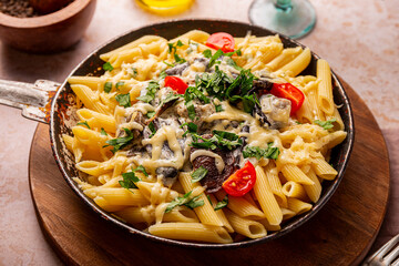Penne pasta with mushroom sauce in a frying pan on the table, vegetarian comfort food