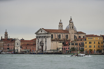 Fototapeta na wymiar Traditional Venetian landscape. Old christian catholic church at the waterfront of Guidecca canal. Venice - 6 May, 2019